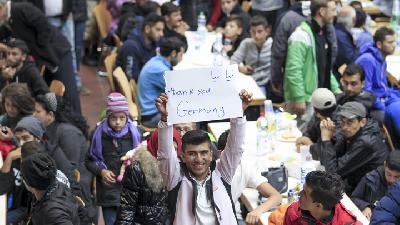 Pengungsi Suriah mengangkat poster terima kasih saat tiba di Jerman. 
