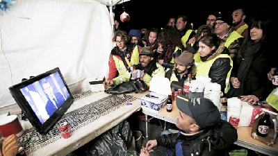 Demonstran Rompi Kuning menyaksikan siaran pers Presiden Emmanuel Macron dari layar televisi, di Marseille, Prancis, 10 Desember 2018. REUTERS