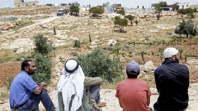 Warga Palestina mengamati alat berat Israel menghancurkan permukiman Palestina di sekitar Hebron, Tepi Barat, 1 Mei 2019./ Reuters/Mussa Qawasma