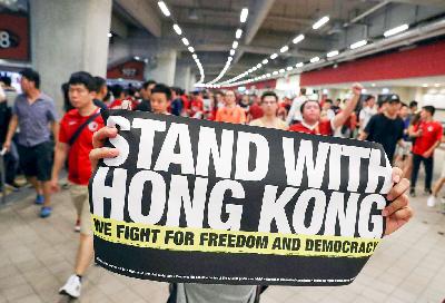 Seorang demonstran memegang tanda mendukung demonstran anti-pemerintah di Stadion Hong Kong, Cina, Selasa lalu. REUTERS/Athit Perawongmetha