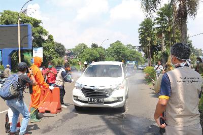 Petugas Dinas Kesehatan Kabupaten Bogor menyemprotkan disinfektan ke mobil dari Jakarta menuju Puncak, Cisarua, Kabupaten Bogor, Sabtu lalu. TEMPO/M.A MURTADHO