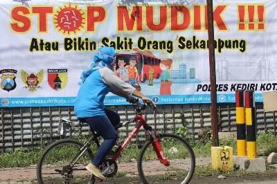 Warga melintas di depan spanduk bertulisan “stop mudik” di Kota Kediri, Jawa Timur, kemarin.