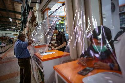 Pekerja melayani pembeli dari balik plastik pembatas di Apotek kawasan Pasar Modern, Tangerang, Banten, Jumat pekan lalu. ANTARA/Fauzan