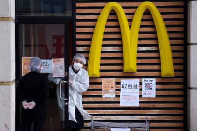 Karyawan menggunakan masker di depan restoran McDonald setelah berakhirnya masa karantina Covid-19 di Wuhan, Cina, kemarin. REUTERS/Aly Song
