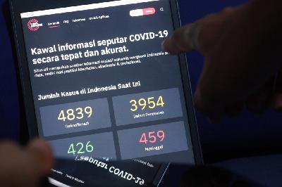 Warga memeriksa data terkini pasien virus corona dalam situs kawalcovid19.id di Pasar Minggu, Jakarta, kemarin. TEMPO/ Nita Dian