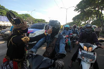 Polisi berpakaian tokoh wayang memeriksa suhu badan warga yang memasuki Surabaya di pintu keluar Jembatan Suramadu, Surabaya, Jawa Timur, kemarin. ANTARA/Didik Suhartono