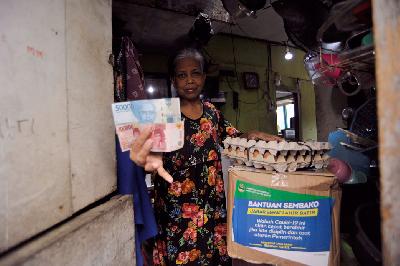 Warga menunjukkan bantuan berupa paket kebutuhan pokok dan uang tunai untuk warga terkena dampak Covid-19 di Bandung, Jawa Barat, 19 April lalu. 