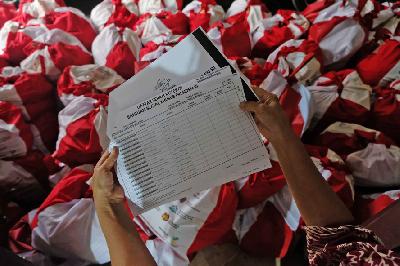 Petugas Rukun Warga memeriksa data warga penerima paket bantuan sosial (bansos) berupa  kebutuhan pokok (sembako) dari Presiden RI sebelum didistribusikan kepada warga terdampak COVID-19 di Pasar Minggu, Jakarta, kemarin.  TEMPO/Nita Dian