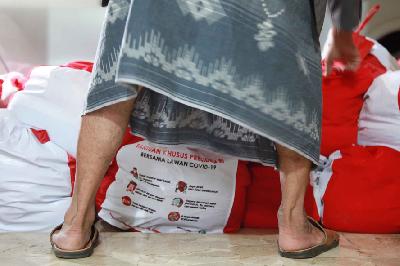 Petugas Rukun Warga menatanpaket bantuan sosial (bansos) berupa  kebutuhan pokok (sembako) dari Presiden RI sebelum didistribusikan kepada warga terdampak COVID-19 di Pasar Minggu, Jakarta, kemarin.  TEMPO/Nita Dian
