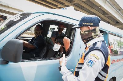 Petugas Dinas Perhubungan DKI Jakarta memberikan masker kepada warga yang tidak menggunakan masker di Check Point Pengawasan Pelaksanaan PSBB di Jalan Raya Kalimalang, Jakarta, 10 April lalu. TEMPO/M Taufan Rengganis