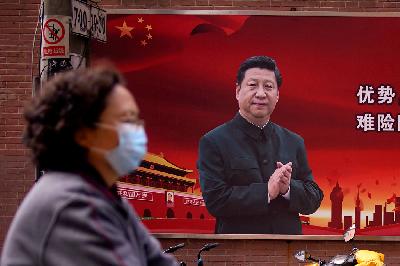 Seorang wanita menggunakan masker ketika melintas di depan foto Presiden Cina XI Jinping, di Shanghai, Cina, 4 April lalu. 