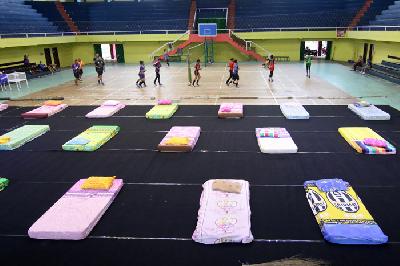 Atlet voli berlatih bersebelahan dengan tempat tidur yang disiapkan untuk karantina pemudik di GOR Tawangalun, Banyuwangi, Jawa Timur, kemarin. 