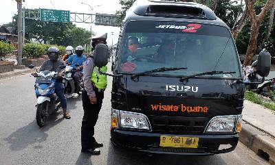 Polisi menindak kendaraan travel saat penerapan pelarangan mudik di Jalur Pantura, Perbatasan Kabupaten Bekasi dengan Karawang, Kabupaten Bekasi, Jawa Barat, Selasa lalu. TEMPO/Hilman Fathurrahman W