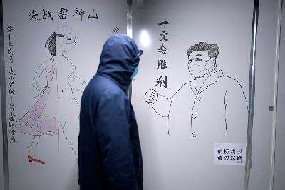 Seorang staf medis mengenakan masker berjalan melewati sketsa Presiden Cina Xi Jinping di bangsal tertutup di Rumah Sakit Leishenshan, rumah sakit darurat bagi pasien yang terinfeksi virus corona, di Wuhan, Hubei, Cina, 11 April 2020. REUTERS / Aly Song