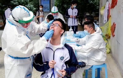 Petugas medis mengenakan hazmat ketika melakukan tes usap swab terhadap siswa Hubei Wuchang Experimental High School sebelum mereka kembali ke sekolah pada 6 Mei, di Wuhan, Cina, 30 April lalu.