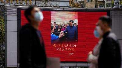 Warga kota Shangai beraktivitas ditengah pandemi corona, dengan latar belakang poster pemerintha Cina dalam menangai Covid-19, di Shangai, Cina, 23 MAret 2020. REUTERS/Aly Song
