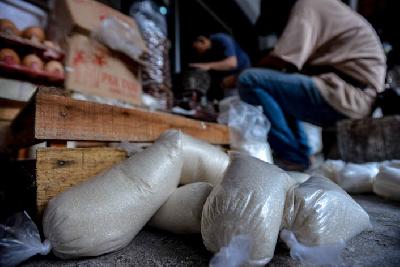 Pedagang membungkus gula pasir kiloan di salah satu agen penjualan bahan pokok di kawasan Kebayoran, Jakarta, 14 April lalu.