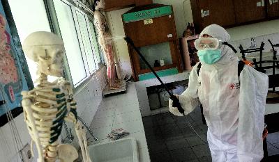 Petugas PMI Jakarta Pusat melakukan penyemprotan cairan disinfektan pada ruang Laboratorium Biologi SMA Negeri 68 Jakarta, di Salemba, Jakarta, 16 Maret 2020. TEMPO / Hilman Fathurrahman W