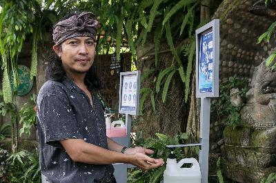 Musisi Gede Robi Supriyanto atau Robi Navicula berpose dengan cairan hand sanitizer dari bahan arak Bali yang terpasang pada prototipe alat pengaplikasiannya di Ubud, Gianyar, Bali, 14 Mei 2020. Johannes P. Christo