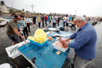 Sejumlah nelayan menjual ikan di lokasi penjualan di tepi pantai di Naples, Italia, ketika negara itu mulai mengakhiri karantina secara nasional imbas virus corona, 17 Mei 2020. REUTERS / Ciro De Luca