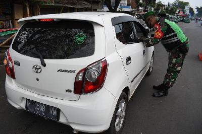 Seorang anggota TNI melakukan screening pengendara mobil di jalur keluar-masuk antar ota di Bandung, Jawa Barat, 27 Mei kemarin.