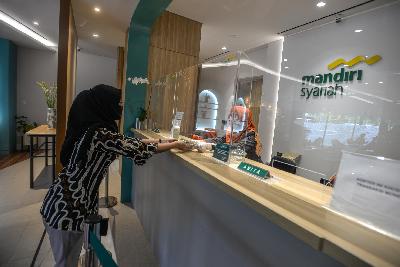 Petugas mengenakan masker dan sarung tangan melayani nasabah di Kantor Cabang Digital Bank Mandiri Syariah Thamrin, Jakarta, 3 Juni 2020. Tempo/Tony Hartawan