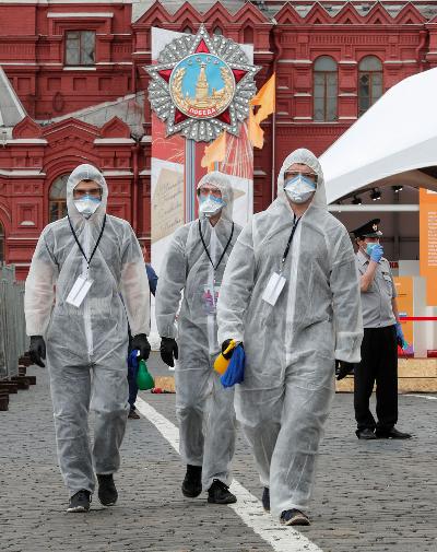 Petugas mengenakan baju pelindung sambil membawa alat disinfektan dalam acara tahunan Festival Buku Lapangan Merah di Moskow, Rusia, 6 Juni lalu.