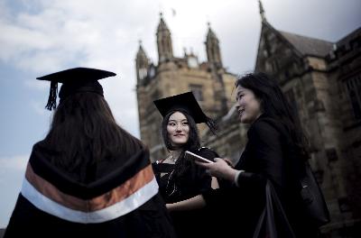 Dua orang mahasiswa mengenakan toga dan topi mortar setelah upacara kelulusannya dari School of Commerce di University of Sydney di Australia. REUTERS/Jason Reed/File Photo