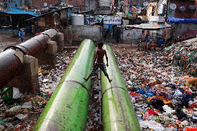 Warga bermain di atas pipa penuh sampah di New Delhi, India 5 Juni 2020. REUTERS / Adnan Abidi