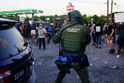 Seorang polisi menodongkan senjata ke arah demonstran yang memprotes penembakan Rayshard Brooks di Atlanta, Georgia, 13 Juni 2020. REUTERS/Elijah Nouvelage