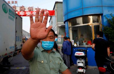 Petugas keamanan menghalangi fotografer mengambil foto di pasar Jingshen, Beijing, Cina yang ditutup karena terdapat kasus covid 19 pada 12 Juni 2020. REUTERS/Thomas Peter