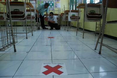 Pegawai menyiapkan tanda jarak sosial di ruang kelas SMAN 5 Bandung, Jawa Barat, 8 Juni 2020. TEMPO/Prima mulia
