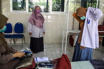 Seorang siswa mencoba seragam sekolah saat mengambil seragam siswa baru di SMA Muhammadiyah 2 (Smamda) Sidoarjo, Jawa Timur, 10 Juni 2020. ANTARA/Umarul Faruq