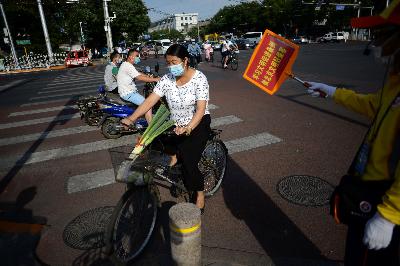 Pengendara sepeda menggunakan masker menyusul penemuan kluster baru Covid 19 di Beijing, Cina, 16 Juni 2020.  REUTERS/Tingshu Wang