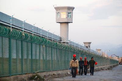 Para pekerja berjalan melewati tembok pembatas yang dikenal sebagai pusat pendidikan keterampilan kejuruan di Dabancheng di Daerah Otonomi Uighur Xinjiang, Cina. REUTERS/Thomas Peter