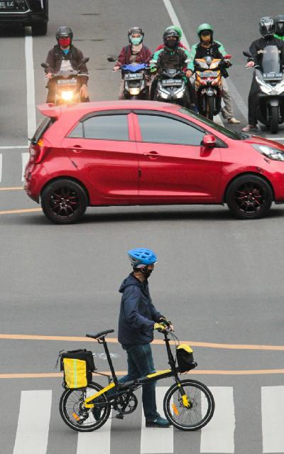 Karyawan menyeberang dengan sepeda usai bekerja di jalan Kebon Sirih, Jakarta, kemarin. TEMPO / Hilman Fathurrahman W