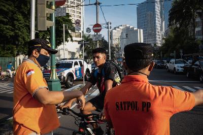 Petugas Satpol PP melakukan penindakan kepada warga yang tidak menggunakan masker saat kegiatan Hari Bebas Kendaran Bermotor (HBKB) di kawasan Bundaran HI, Jakarta, 21 Juni 2020.  TEMPO/M Taufan Rengganis