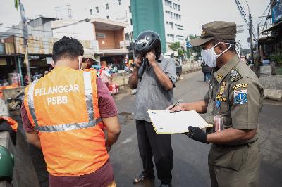 Warga yang tidak menggunakan masker diberikan sanksi menyapu jalan oleh petugas Satpol PP di kawasan Pasar Minggu, Jakarta, 23 Juni 2020. TEMPO/M Taufan Rengganis