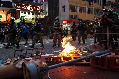 Polisi anti-huru-hara berjalan melewati tumpukan barang yang dibakar pengunjuk rasa penentang Undang-Undang Keamanan Nasional saat pawai memperingati 23 tahun penyerahan Hong Kong dari Inggris ke Cina, 1 Juli lalu.