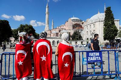 Warga mengenakan bendera Turki setelah putusan pengadilan mengubah Hagia Sophia menjadi masjid pada Jumat lalu. REUTERS/Murad Sezer