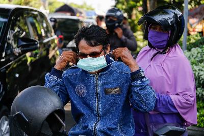 Pengendara motor menggunakan masker yang diberikan petugas usai terjaring operasi pengendara tanpa masker guna mencegah penyebaran wabah virus corona (Covid-19) di Denpasar, Bali, 17 April 2020. Johannes P. Christo