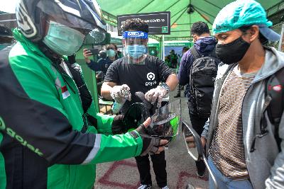 Pengemudi Gojek melakukan penyemprotan disinfektan pada kendaran dan helm di Kawasan Stasiun Sudirman, Jakarta Pusat, 8 Juni 2020. Tempo/Tony Hartawan