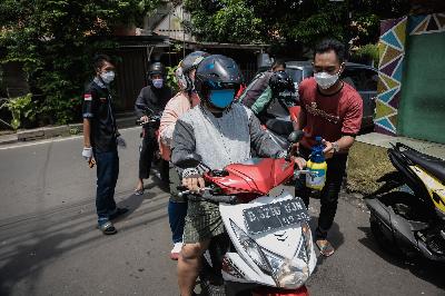Warga menyemprotkan cairan disinfektan ke motor pengendara diakses masuk ke permukiman warga di Kali Pasir Cikini, Jakarta, 1 April 2020. TEMPO/M Taufan Rengganis