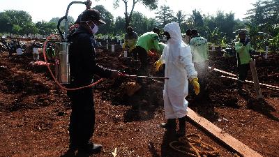 Petugas pemakaman disemprot dengan cairan desinfektan di TPU Pondok Ranggon, Jakarta, 16 Mei 2020. TEMPO/Hilman Fathurrahman W