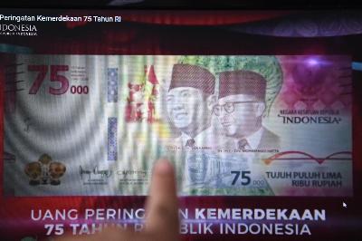 Warga memotret layar yang menampilkan uang lembar pecahan Rp75.000 saat diluncurkan secara virtual, di Jakara, 17 Agustus 2020. ANTARA/Hafidz Mubarak A