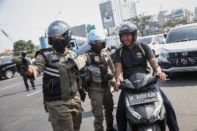 Petugas melakukan penindakan kepada pengendara yang tak menggunakan masker di Jalan Raya Margonda, Depok, Jawa Barat, 23 Juli 2020. TEMPO/M Taufan Rengganis