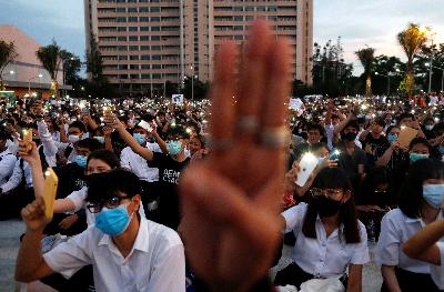 Para siswa mengangkat tangan membentuk  tiga jari dan menggunakan ponsel sebagai senter untuk mendukung gerakan pro-demokrasi yang dipimpin siswa di Institut Teknologi Raja Mongkut, Bangkok, Thailand, Rabu pekan lalu. REUTERS / Jorge Silva 