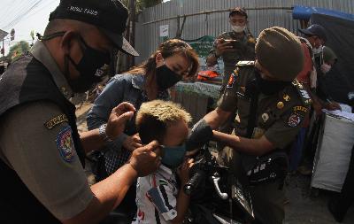 Petugas pemkot Depok memasang masker  kepada anak saat razia PSBB di Sawangan, Depok, Jawa Barat, 25 Agustus 2020. Tempo/Amston Probel