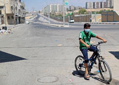 Warga Palestina bersepeda di kamp pengungsi Pantai saat lockdown akibat wabah Covid-19  di Kota Gaza, 27 Agustus 2020. REUTERS/Mohammed Salem