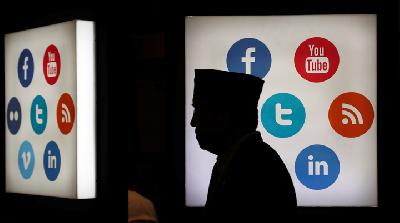 Seseorang melintas di depan papan yang memuat platform media sosial di Jakarta, Oktober 2017. REUTERS/Beawiharta 